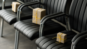 A row of black leather chairs with gift boxes placed on each seat signifying corporate gifts.