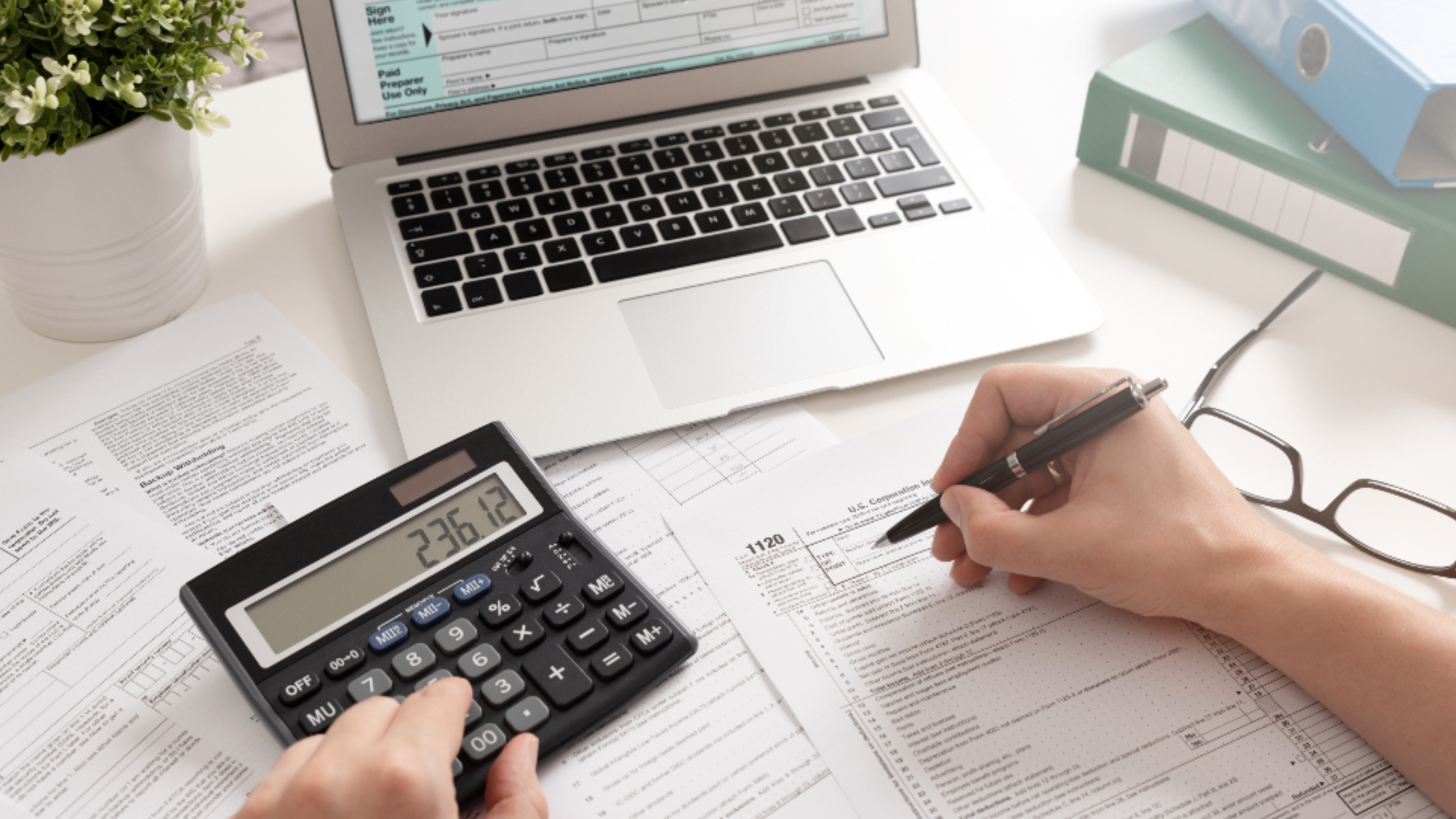 A person filling out tax free voucher paperwork using a laptop and calculator 