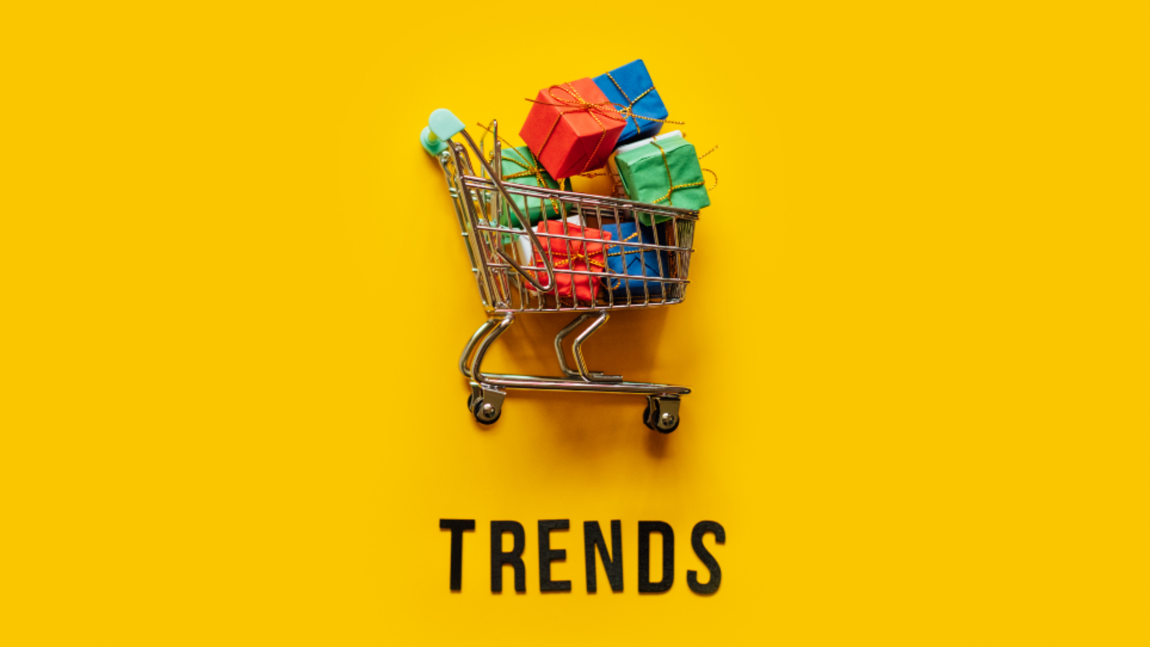 An image of a trolley full of wrapped presents on a yellow background with the word “trends” underneath.