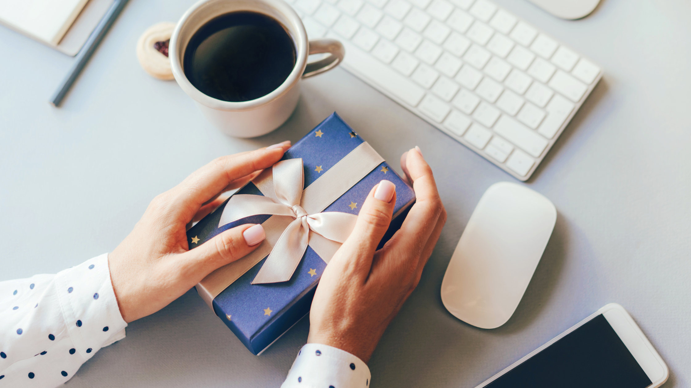 An employee holding a gift or christmas bonus from their employer at their desk