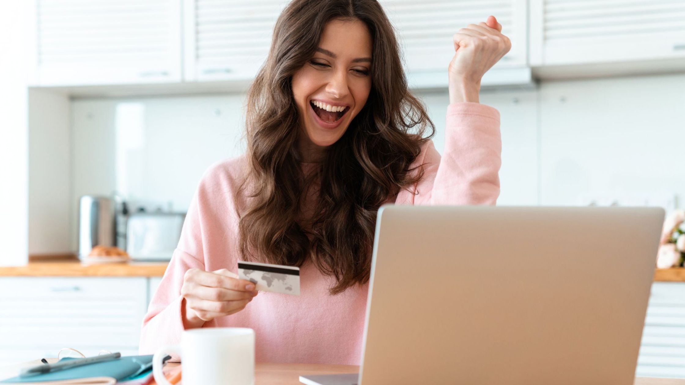 A woman sits at a table with her laptop and SWIRL Prepaid Card Successfully shopping online