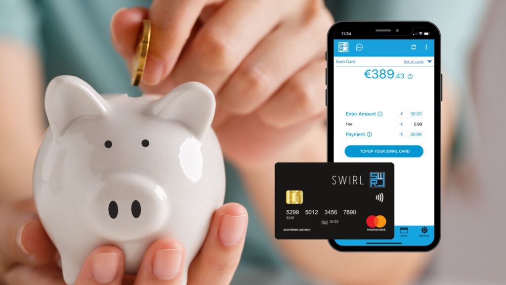 Holding a piggy bank inserting coins with a SWIRL Mastercard phone app open to show savings